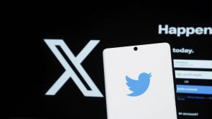 Ein Smartphone, das das Twitter Logo vor einem schwarzen Hintergrund mit einem weißen X zeigt A smartphone displaying th
